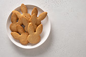 Easter cookies shaped of bunny in white plate. Festive food and kids snacks.