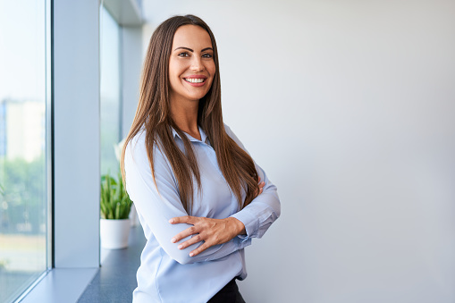 Portrait of smiling confident middle aged businesswoman standing at office
