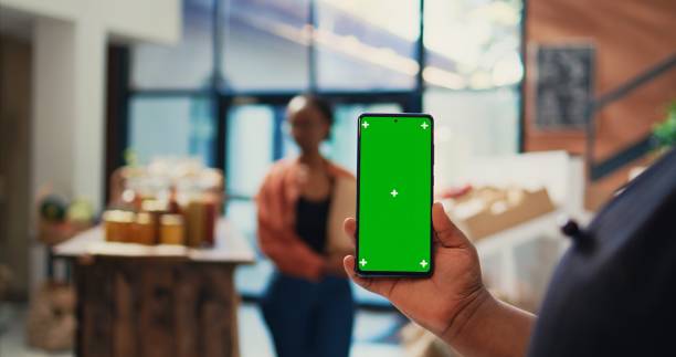istock Retailer holding mobile phone with greenscreen layout 1969719040