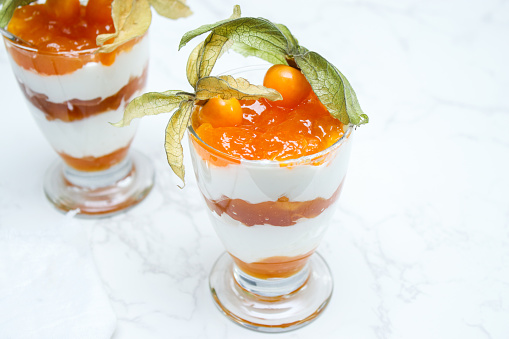 Two glasses jar of layered dessert with protein yoghurt and physalis fruit
