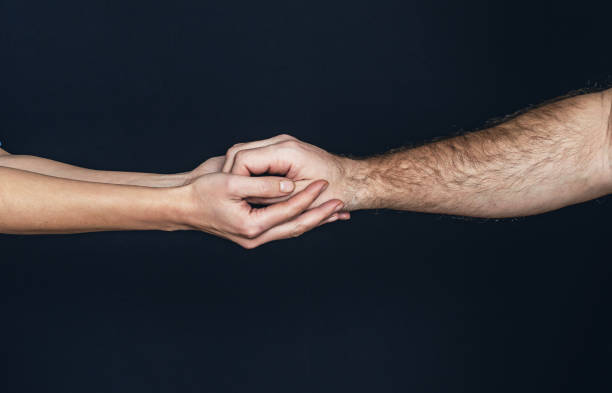 istock Female hands holding male hand gently, support on black background 1969771226