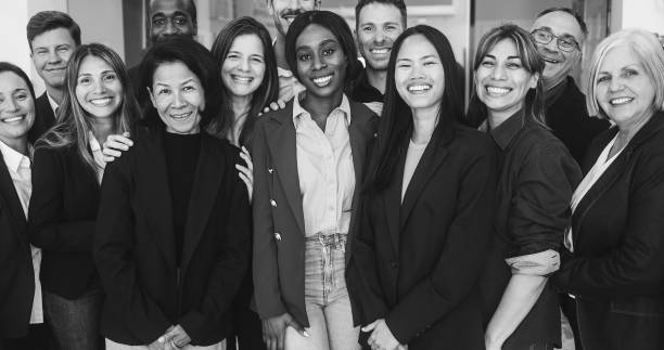 istock Multigenerational workers smiling in front of camera inside business office - Multiracial, job employees, entrepreneur and teamwork concept - Main focus on african girl face - Black and white editing 1969771242