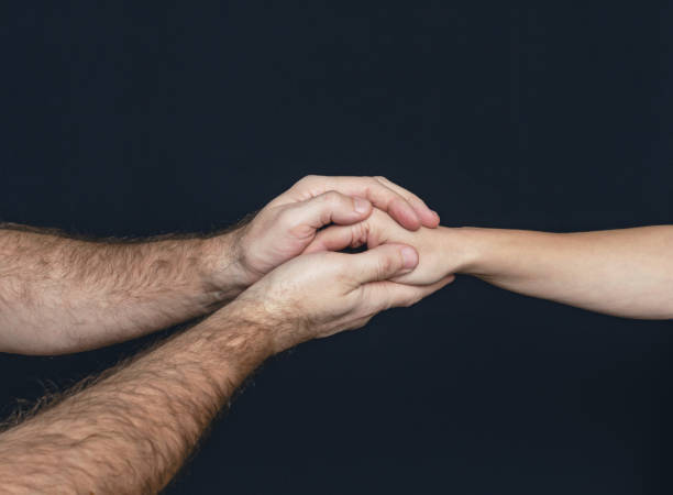 istock A man hand holds woman hand gently on black background 1969771249