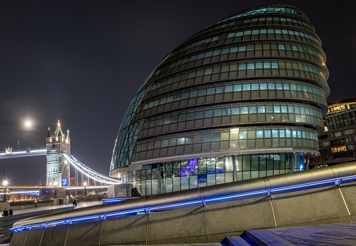 London. UK-01.27.2024. A night time view of City Hall with Tower Bridge in the background. The London mayor's office and administrative building.