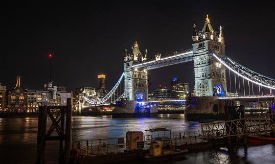 The gothic battlements of Tower Bridge illuminated at night over the River Thames in the heart of London, UK.