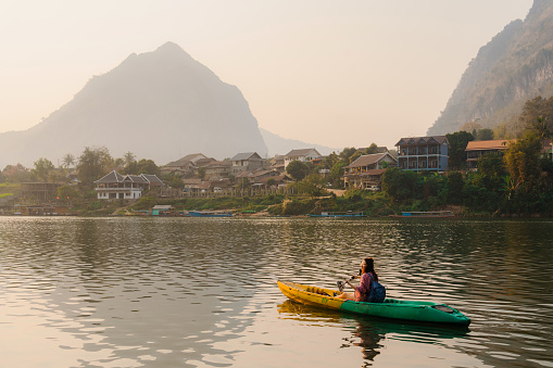 Cheerful woman  canoeing on Mekong river in Laos  at sunset