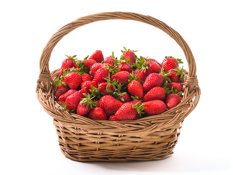 Vintage basket full of freshly harvested ripe strawberries, vibrant red healthy and yummy fruits, isolated on white