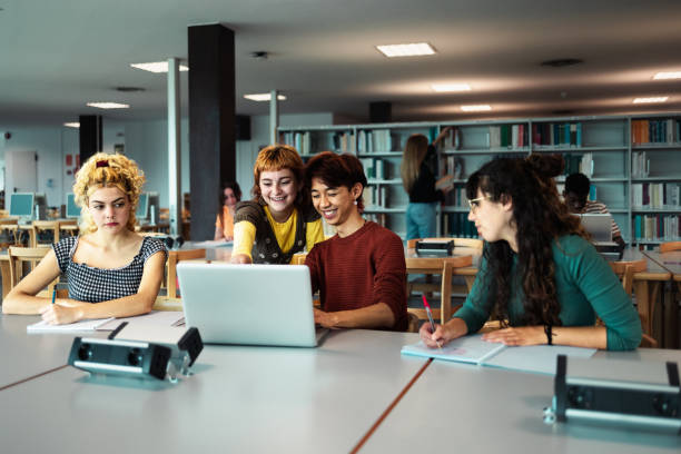 istock Young university students using laptop and studying with books in library - School education concept 1969830542