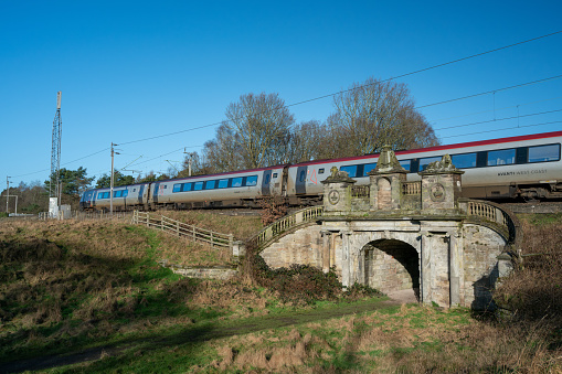 COLWICH, STAFFORDSHIRE, ENGLAND. JANUARY 2024. Avanti train travelling over an ornate railway bridge on the West Coast mainline railway.