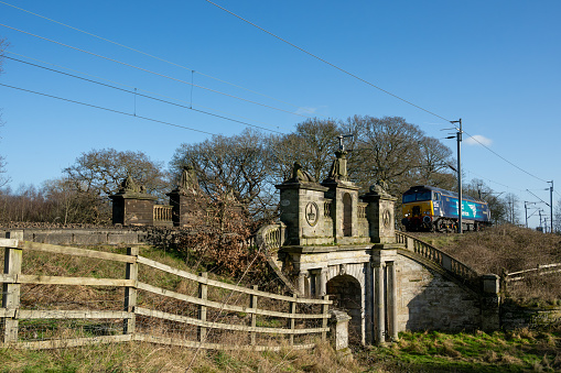 COLWICH, STAFFORDSHIRE, ENGLAND. JANUARY 2024. Direct Rail Services locomotive train travelling over an ornate railway bridge on the West Coast mainline railway.