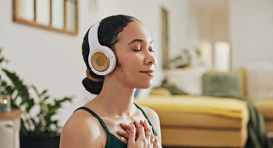 Meditation, woman with hands on chest for mindfulness and zen, headphones for wellness and healing with tech. Yoga, listening to music or podcast for self care, holistic healing and calm at home