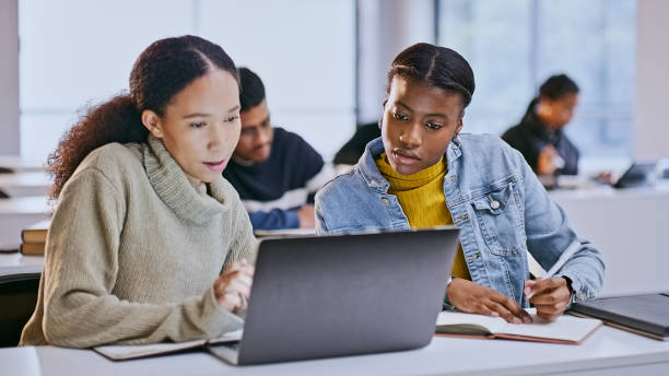 istock Students, women and teamwork in classroom with laptop for elearning, research and writing college notes. University, diversity and friends with technology, studying and books for education or exam 1969855099