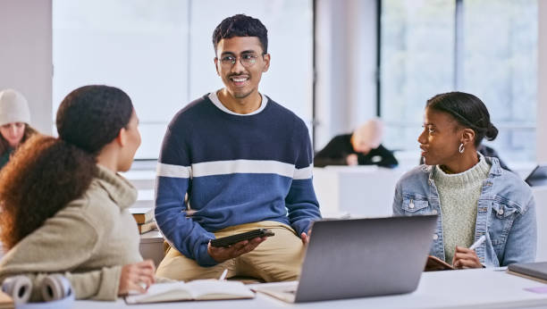 istock Students, group and technology in college classroom with learning, research and brainstorming discussion. University, diversity and teamwork with laptop, tablet and books for education or exam study 1969855273