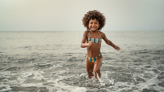 Afro child having fun playing inside sea water during summer holidays - Childhood and travel vacation concept