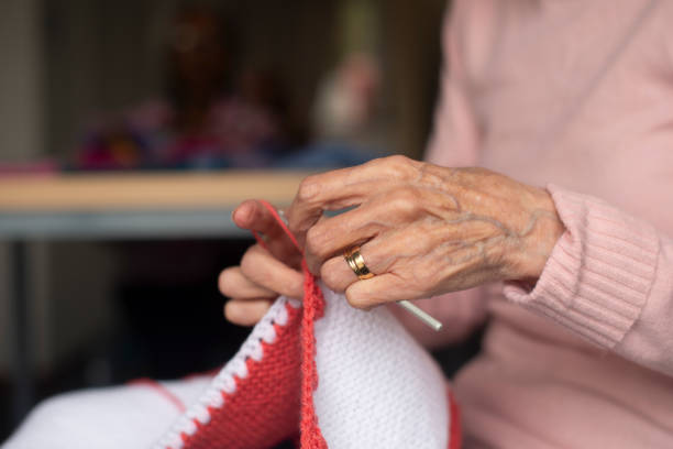 Elderly, person and hands with wool for knitting in retirement home with handcraft, thread or closeup. Senior, hobby and needles with sewing or crochet and yarn in hospice for handmade activity