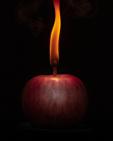 A glowing light emanates from apple against dark backdrop