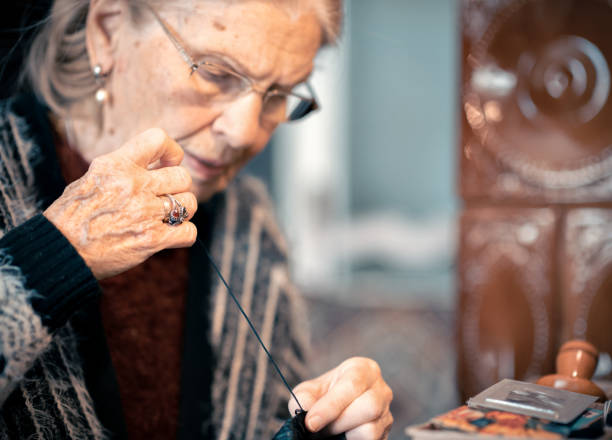 istock Elderly lady sewing at home. Concentrated with a sewing needle in her hand 1969903843