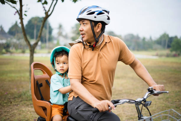 istock Father carrying his son riding bicycle in park 1969916553