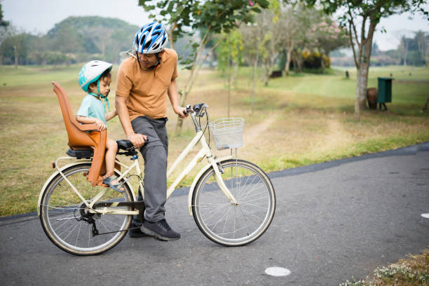 Father carrying his son riding bicycle in park