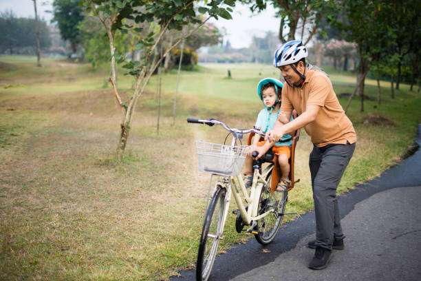 istock Father carrying his son riding bicycle in park 1969917600