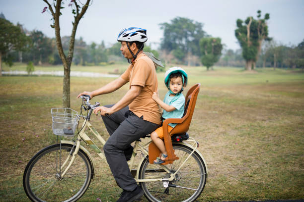 Father carrying his son riding bicycle in park