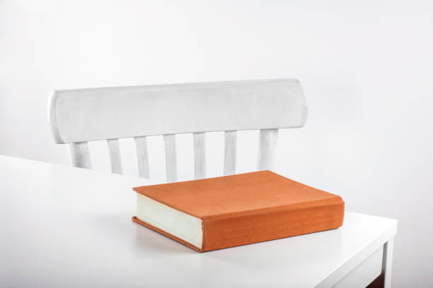 istock Closed book on a white table with a chair 1969923889
