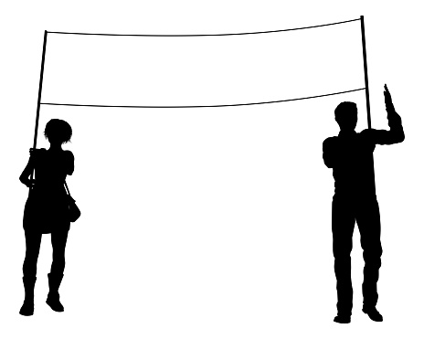 Two protestors or demonstrators at a demonstration march, picket line or strike protest rally in silhouette. Holding up a banner sign.