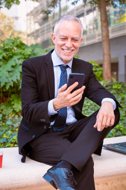 istock Smiling businessman using an app on his smartphone sitting outdoors .vertical 1969940671