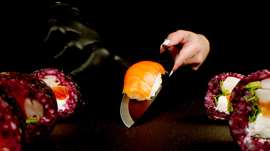 Variety of types of sushi with red caviar, fish, Philadelphia cheese close-up. Set of delicious Japanese sushi rolls on a black background. The concept of advertising healthy and tasty seafood food.