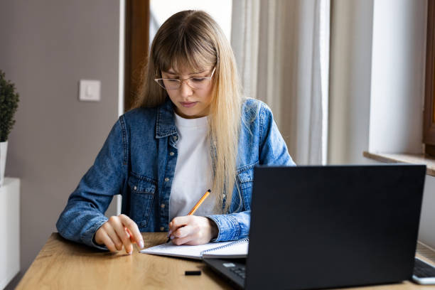 istock Young female freelancer with laptop working or studying online at home 1969949985