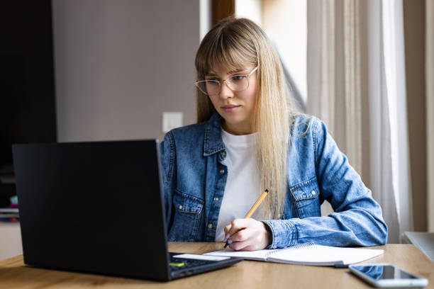 istock Concentrated young woman studying or working online using laptop sitting at home 1969954748