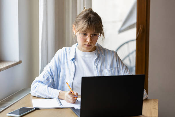 istock Concentrated young woman studying or working online using laptop sitting at home 1969955253