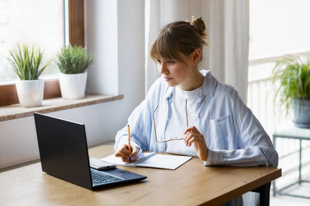 istock Young female freelancer with laptop working or studying online at home 1969956337