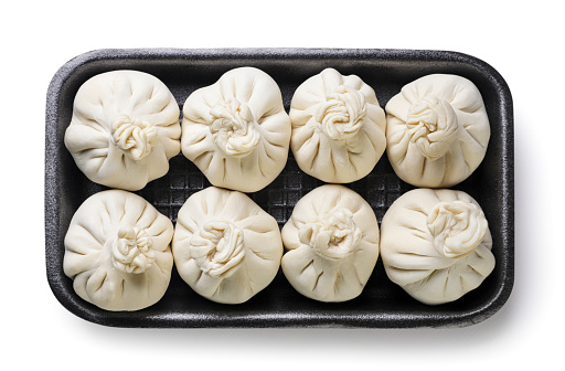 Close-up, top view of traditional Asian/Chinese dumplings in blue plate with soy sauce and chopsticks on gray rustic stone background. Authentic Chinese cuisine