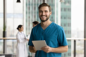 Cheerful handsome surgeon doctor man holding digital tablet computer