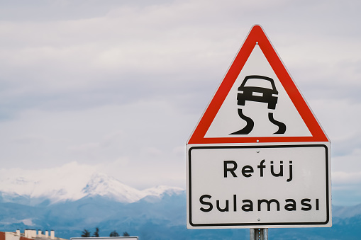 Refuj sulamasi inscription in Turkish means that part of road may be wet and slippery due to irrigation of rain. Road sign slippery when wet. Skidding danger due to hydroplaning