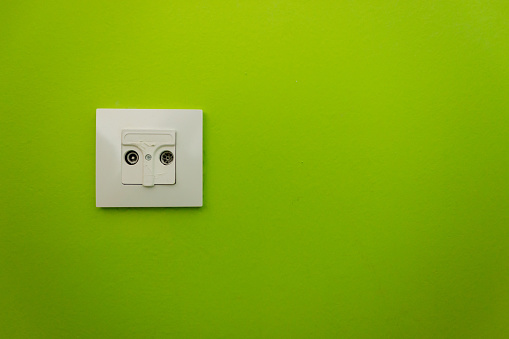 Cable outlet on a lime green wall in a modern setting.