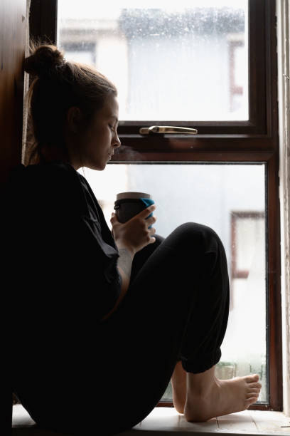 istock woman sitting at the window 1970026512