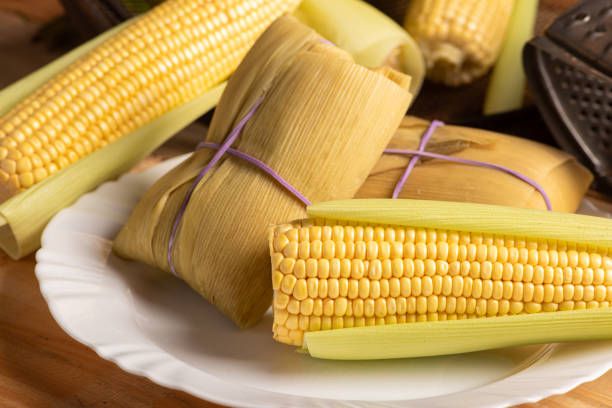 istock Pamonha and green corn, Pamonha on a white plate and beautiful ears of green corn on rustic wood, selective focus. 1970029709