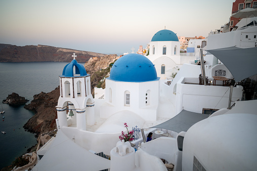 View of Oia white washed buildings with the famous three blue domes church taken at sunrise...