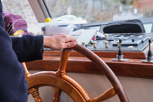 Close up of a captain hand, on a touring boat, holding the helm.