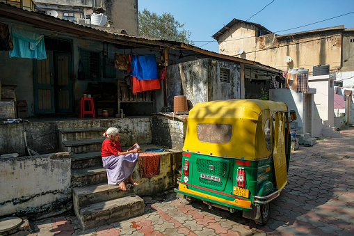 Ahmedabad, India - January 12, 2024: A woman sits next to an autorickshaw in Ahmedabad, Gujarat, India.