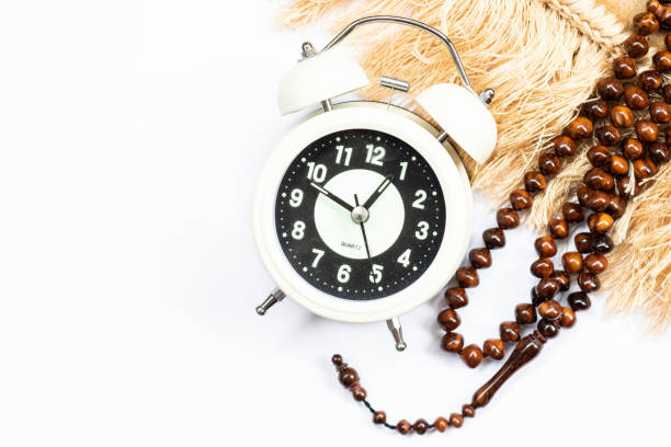 Time to break the fast, alarm clock and prayer beads on a white background.
