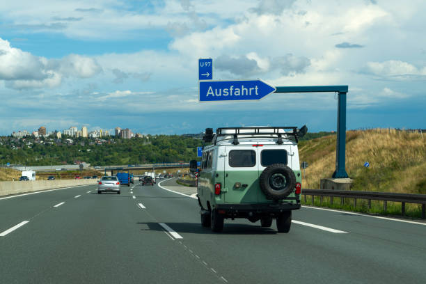 синий знак автострады над дорогой в германии при движении микроавтобуса по дороге. германия. - ausfahrt стоковые фото и изображения