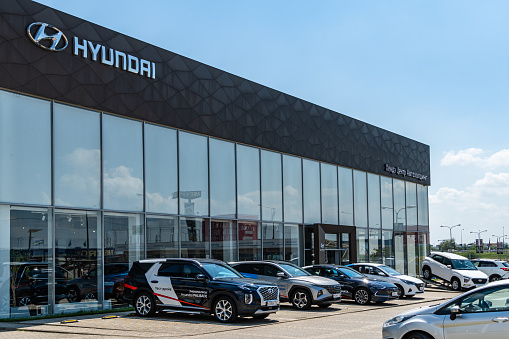 Cars of different colors are parked outside Hyundai dealership. On facade of building there is an inscription Hyundai with logo. Hyundai dealership. Mega Adygea. Krasnodar, Russia - August 04, 2022