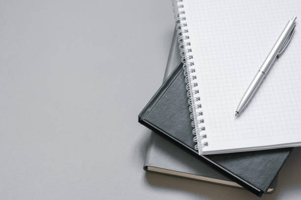 istock Stylish workplace. Notebooks and diaries on a gray desktop with a pen. Copy space 1970101202
