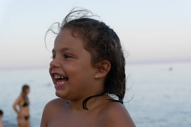 portrait of a girl smiling on the beach at sunset with the sea in the background