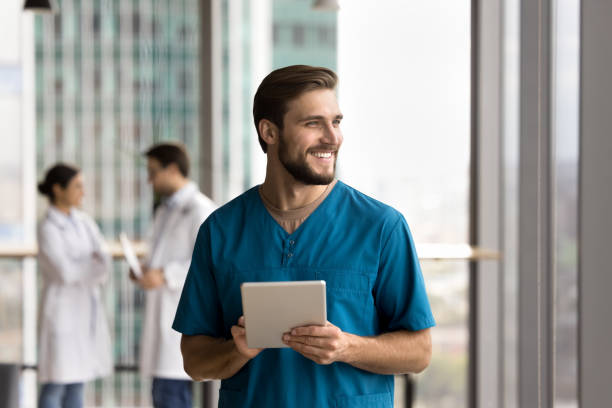istock Happy handsome doctor man in blue uniform holding digital tablet 1970104382