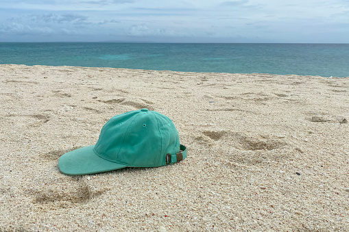 Forgotten cap on a sandy beach against the blue sea.