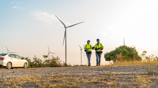 Two engineers working together discussing wind power projects and work in wind farm.Engineering expert or renewable energy for wind, power and clean energy concept.